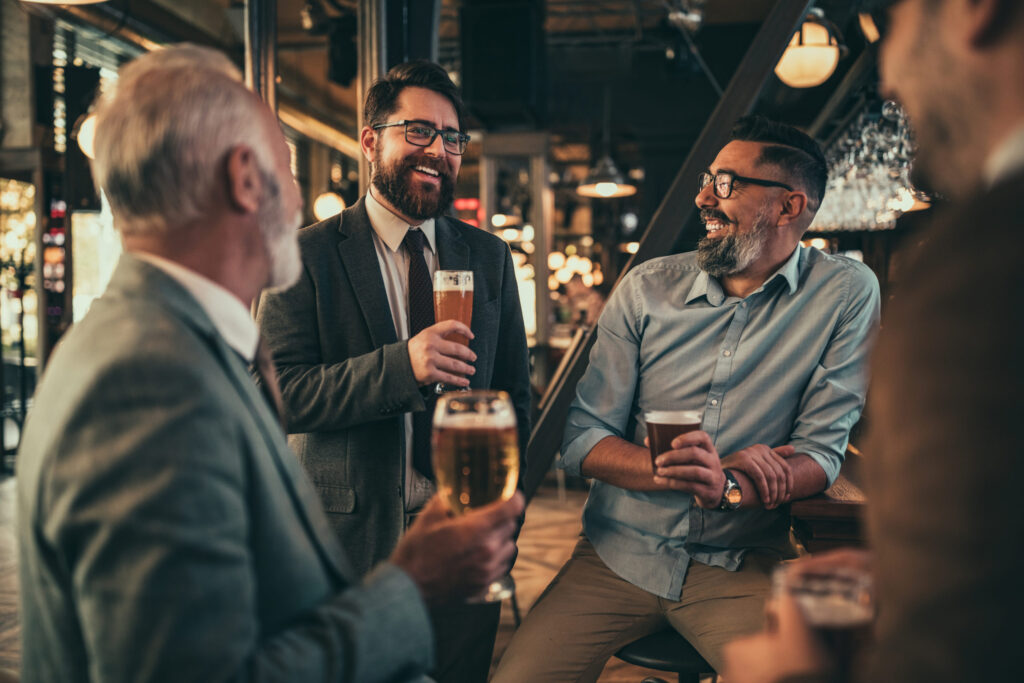 Group of men enjoying drinks in a restaurant setting, illustrating a welcoming hometown environment.