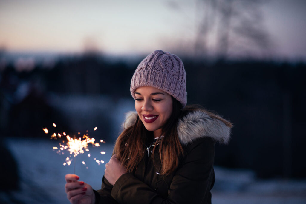 Woman smiling and holding sparklers, revitalizing lifestyle and self-care.