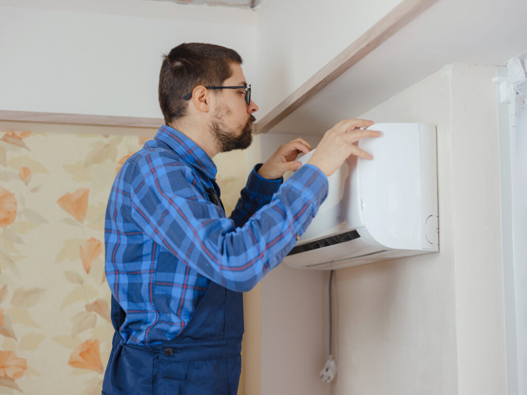 Man inspecting wall-mounted HVAC system for maintenance and repair.
