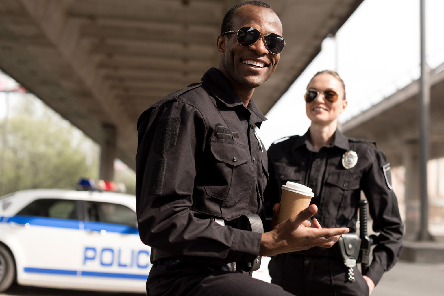 a man and a woman standing in front of a police car