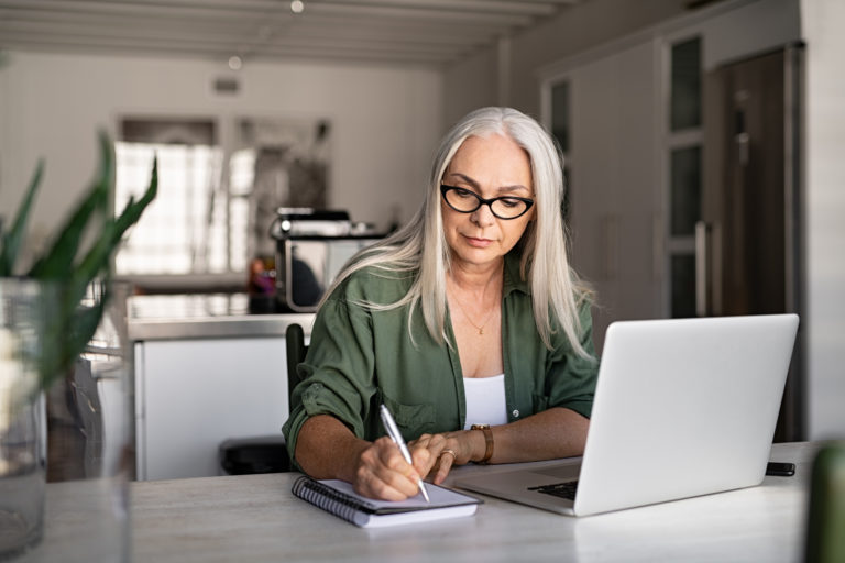 a woman sitting at a table with a laptop and pen