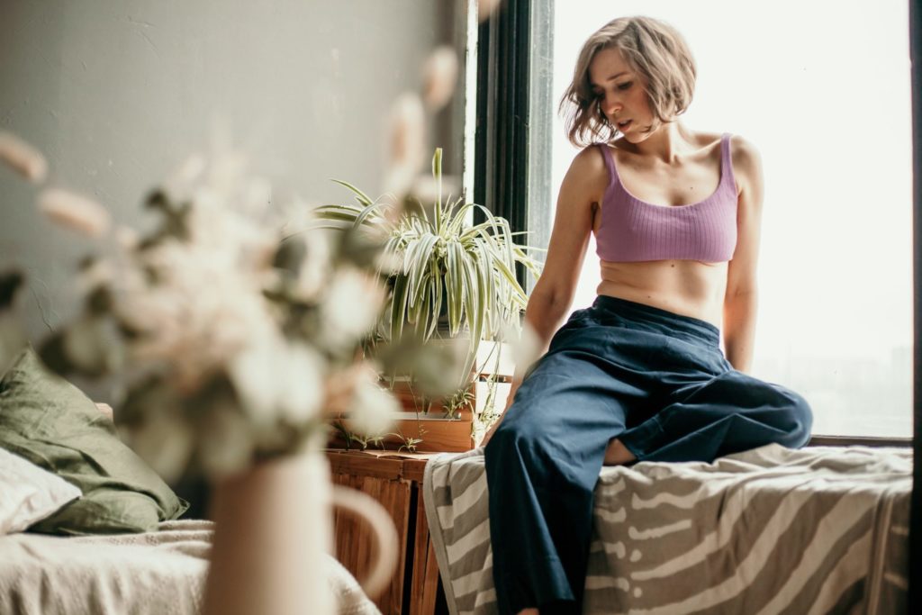 A woman is sitting on the sill of a large window. Contour light