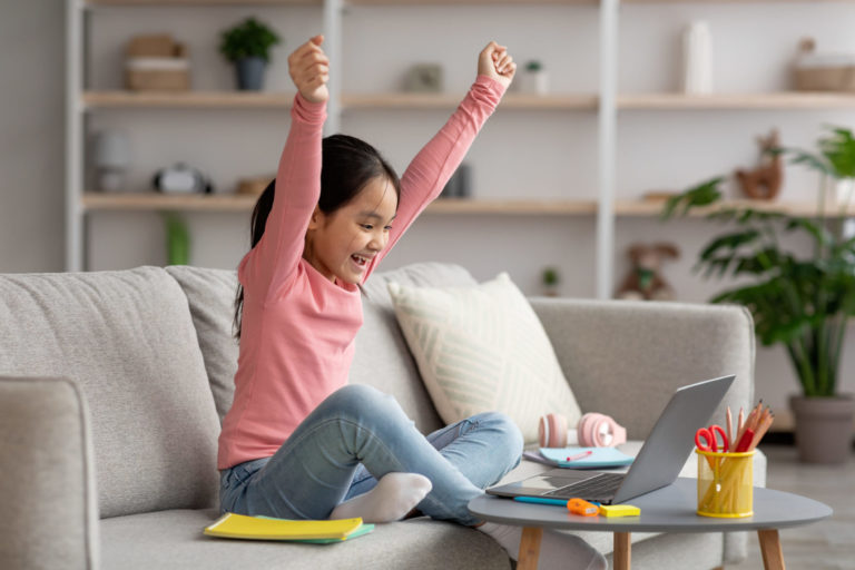 Happy korean schooler celebrating success, home interior